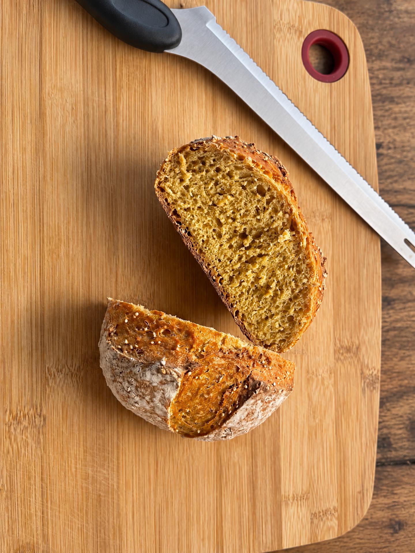 A halved sourdough boule showing its golden crumb on a bamboo board