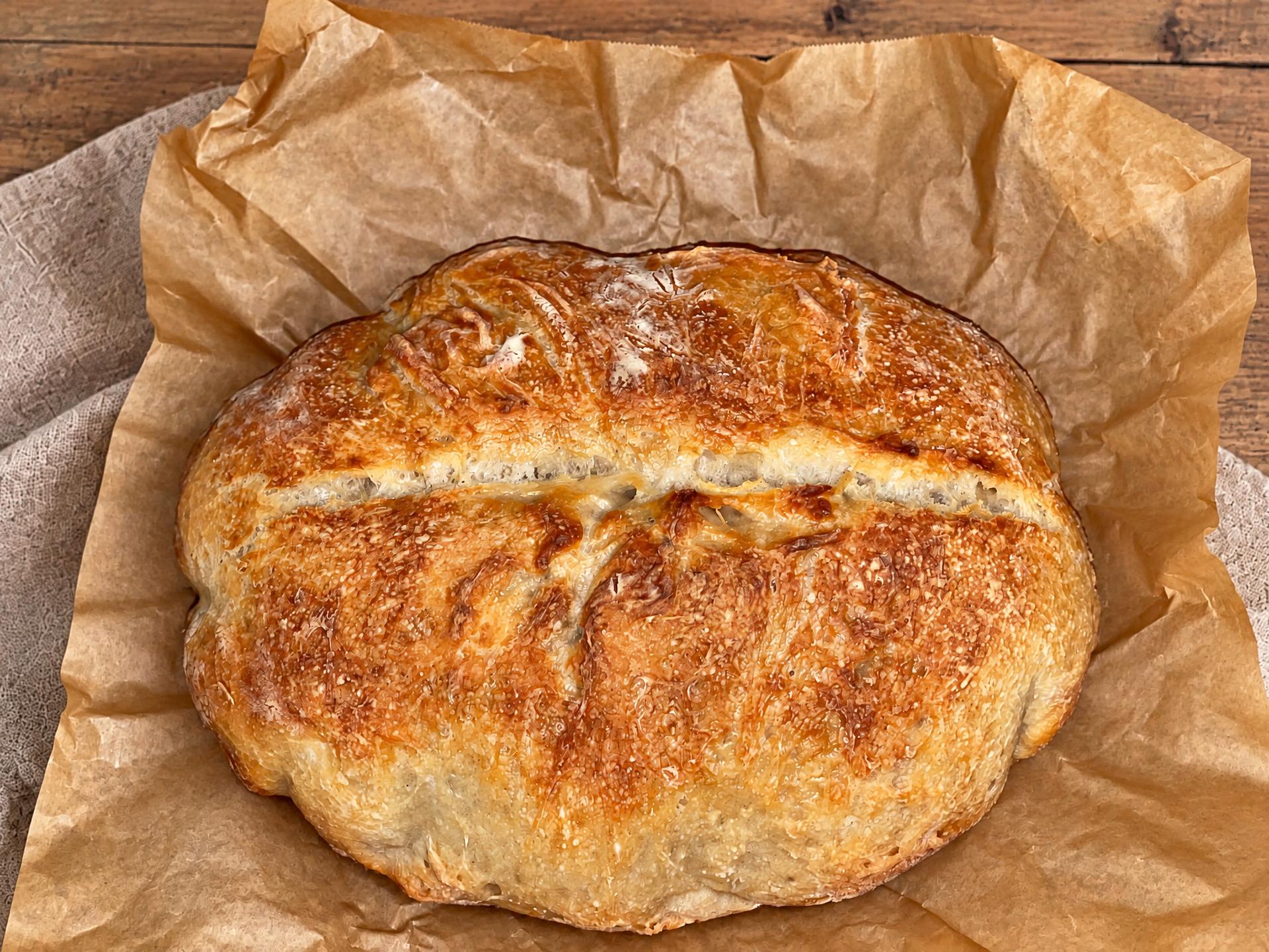 Whole rustic sourdough boule on parchment paper
